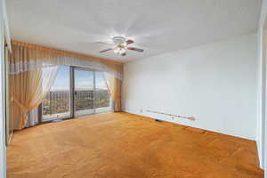 Carpeted spare room featuring a textured ceiling and ceiling fan