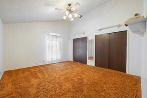 Unfurnished bedroom with a textured ceiling, carpet flooring, high vaulted ceiling, and ceiling fan