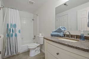 Full bathroom featuring toilet, vanity, tile patterned flooring, and shower / bath combo with shower curtain