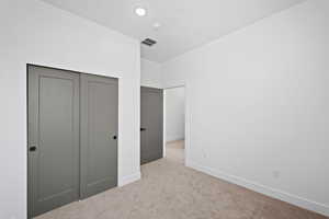 Unfurnished bedroom with light colored carpet and a closet