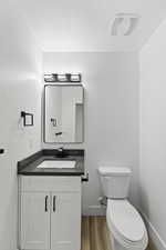 Bathroom featuring vanity, toilet, hardwood / wood-style flooring, and a textured ceiling