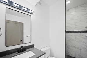 Bathroom with vanity, toilet, and tiled shower