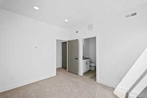 Unfurnished bedroom featuring light carpet and ensuite bathroom