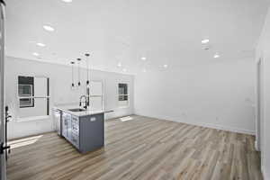 Kitchen with stainless steel appliances, pendant lighting, gray cabinetry, light hardwood / wood-style floors, and sink