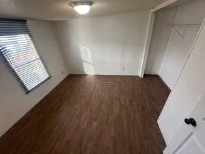 Unfurnished bedroom featuring a closet, dark hardwood / wood-style floors, and a textured ceiling