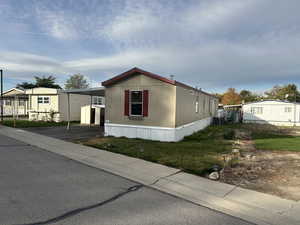 Manufactured / mobile home featuring a carport, cooling unit, and a front lawn