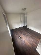 Empty room featuring a textured ceiling and dark wood-type flooring