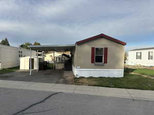 Manufactured / mobile home featuring a storage shed and a front lawn