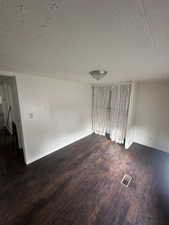 Spare room featuring dark hardwood / wood-style floors and a textured ceiling