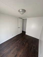 Empty room with a textured ceiling and dark hardwood / wood-style floors