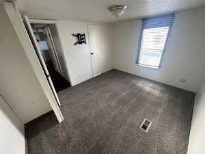 Carpeted empty room with a textured ceiling