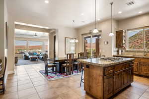 Kitchen with stainless steel gas cooktop, a center island, ceiling fan with notable chandelier, and plenty of natural light