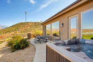 View of patio with a hot tub and a mountain view