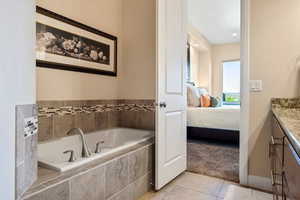 Bathroom with vanity, tiled bath, and tile patterned floors