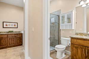 Bathroom with toilet, an enclosed shower, and vanity