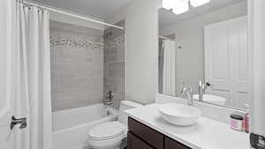 Full bathroom featuring vanity, toilet, and shower / tub combo with curtain