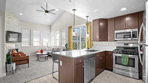 Kitchen featuring kitchen peninsula, appliances with stainless steel finishes, a kitchen breakfast bar, light hardwood / wood-style flooring, and sink