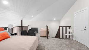 Carpeted bedroom featuring lofted ceiling and a textured ceiling