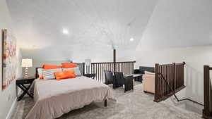 Bedroom featuring a textured ceiling, vaulted ceiling, and light colored carpet