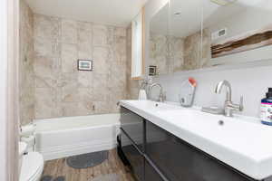 Full bathroom featuring vanity, toilet, wood-type flooring, and tiled shower / bath