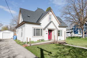 View of front of house featuring a front yard, a garage, an outbuilding, and a wooden deck