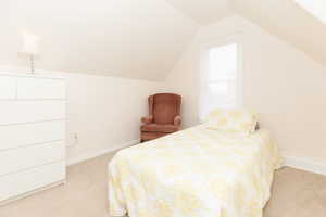 Bedroom with lofted ceiling and light colored carpet