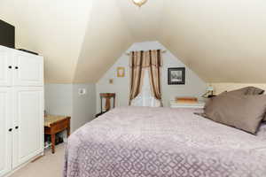 Carpeted bedroom featuring a closet and vaulted ceiling