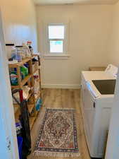 Washroom with washer and dryer and light hardwood / wood-style flooring