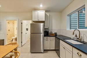 Kitchen with decorative backsplash, stainless steel appliances, white cabinets, and sink