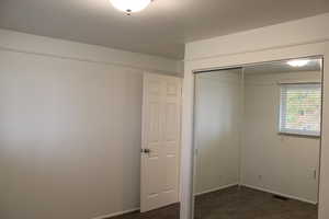 Unfurnished bedroom featuring dark carpet and a closet