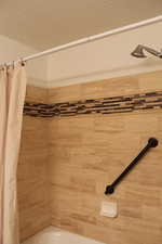 Bathroom with shower / bath combination with curtain and a textured ceiling