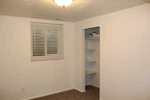 Unfurnished bedroom featuring a closet and dark colored carpet