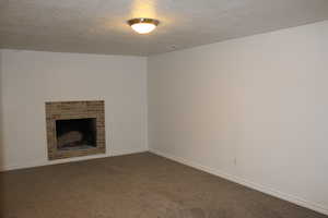 Unfurnished living room with a textured ceiling, a fireplace, and carpet flooring