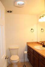 Bathroom featuring vanity, toilet, tile patterned floors, and a textured ceiling