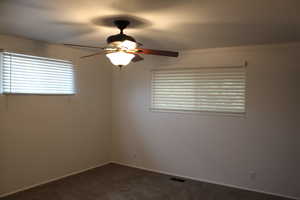 Carpeted spare room featuring a healthy amount of sunlight and ceiling fan