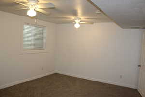 Carpeted empty room featuring a textured ceiling and ceiling fan