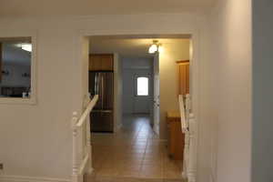 Hallway with crown molding and light tile patterned floors