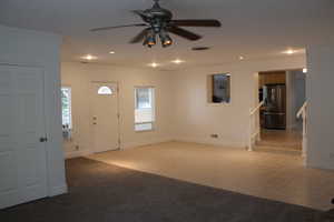 Carpeted entrance foyer with crown molding and ceiling fan