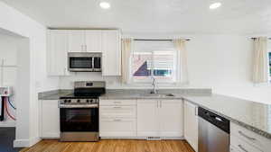 Kitchen featuring white cabinetry, sink, appliances with stainless steel finishes, and light hardwood / wood-style flooring