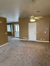 Carpeted spare room with ceiling fan and a textured ceiling