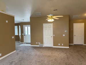 Unfurnished room featuring a textured ceiling, ceiling fan, and light carpet