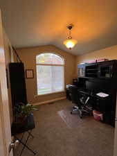 Carpeted office space/bedroom featuring vaulted ceiling