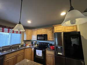 Kitchen featuring black appliances, sink, and decorative light fixtures