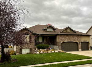 View of front of home featuring a front yard, covered porch, and a garage