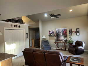 Carpeted living room with ceiling fan and lofted ceiling