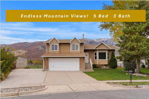 View of front of house with a garage, a mountain view, and a front lawn