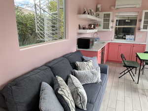 Living room i n pool house  with an AC wall unit, sink, and light hardwood / wood-style flooring