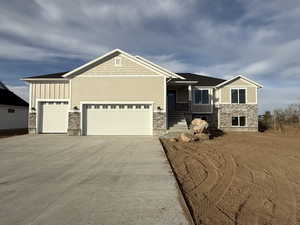 Craftsman-style home with concrete driveway, stone siding, board and batten siding, and an attached garage