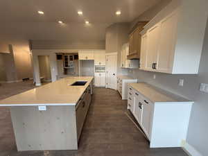 Kitchen with white cabinets, a large island, and dark hardwood / wood-style floors