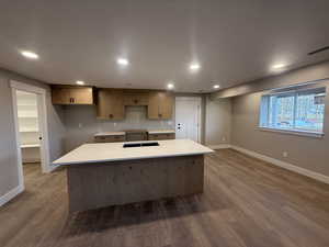 Kitchen featuring a large island, hardwood / wood-style floors, and light stone countertops